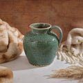 Antique green stoneware urn vase featuring a reactive glaze, rounded body, single side handle, and wide mouth